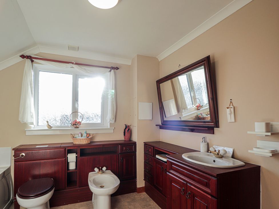 A bathroom with a toilet, bidet, sink and window at Arnaval in Carbost
