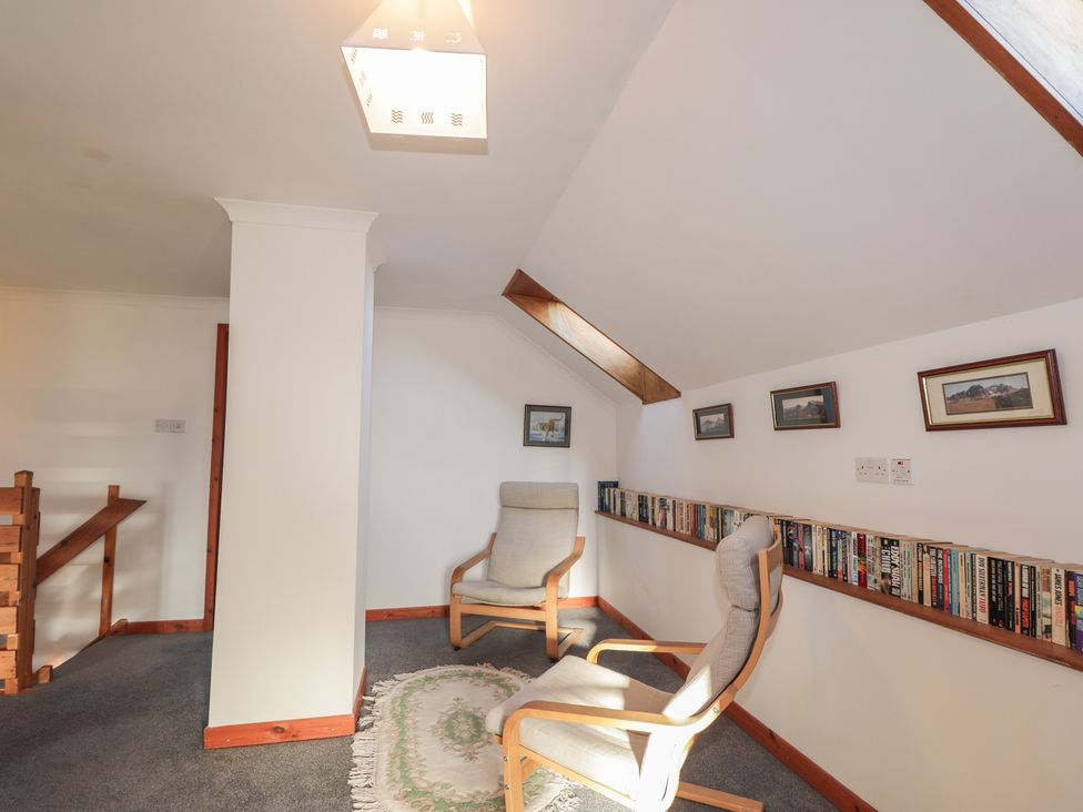 A sitting room with two chairs and a bookshelf filled with books at Arnaval in Carbost