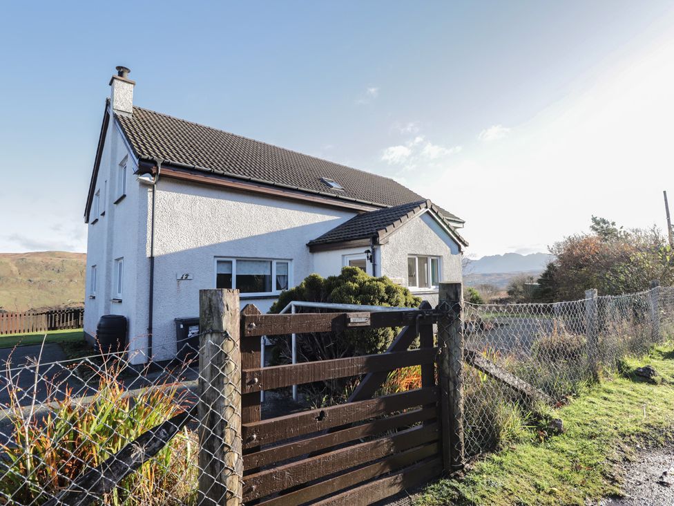 A house with a wooden gate and fence in front at Arnaval in Carbost