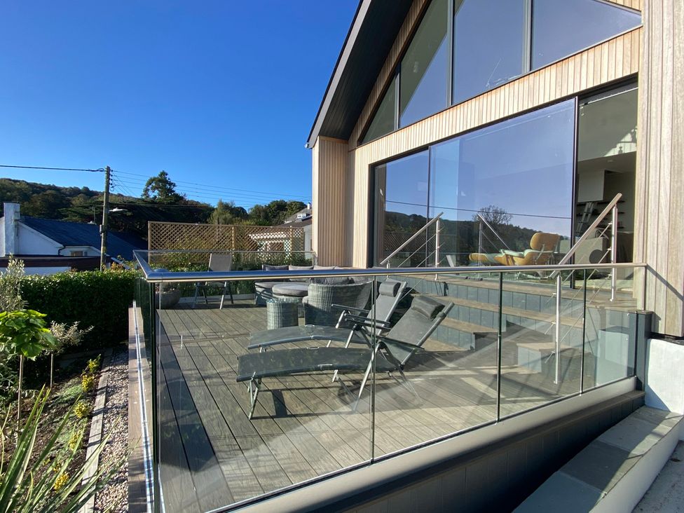 A deck with chairs and table at Woodcroft in Pwllheli
