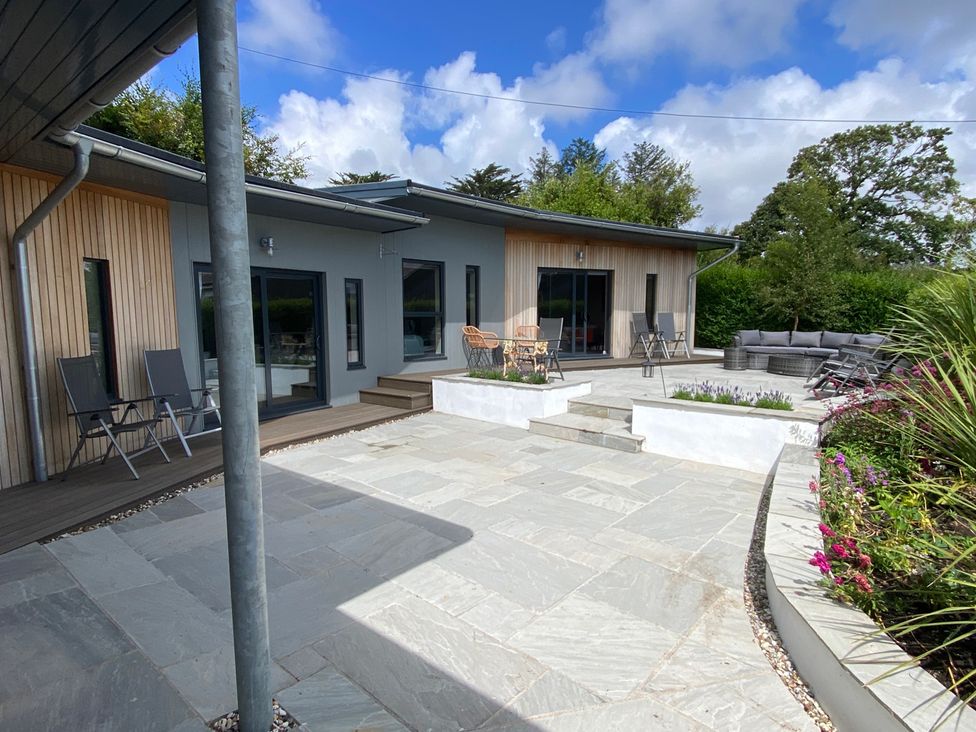 An outdoor area with a house and seating at Woodcroft in Pwllheli