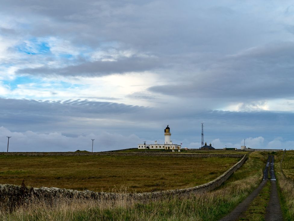 A landscape featuring a lighthouse and a road at The Lighthouse Keepers Cabin Noss Head near Wick, Caithness