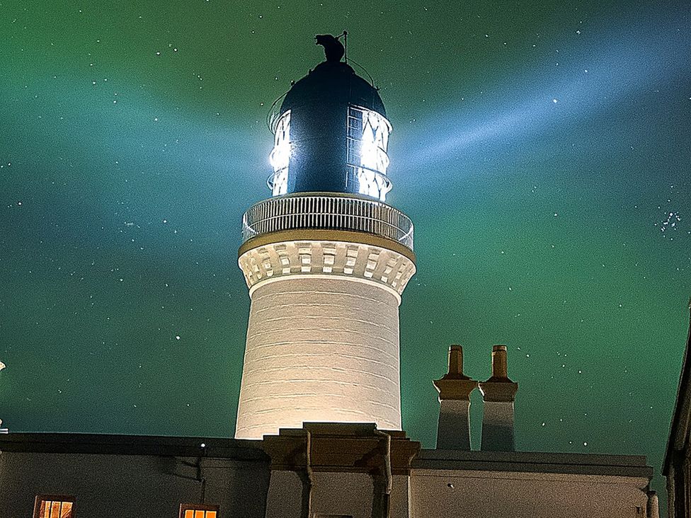 A lighthouse with a light beam at The Lighthouse Keepers Cabin Noss Head near Wick Caithness
