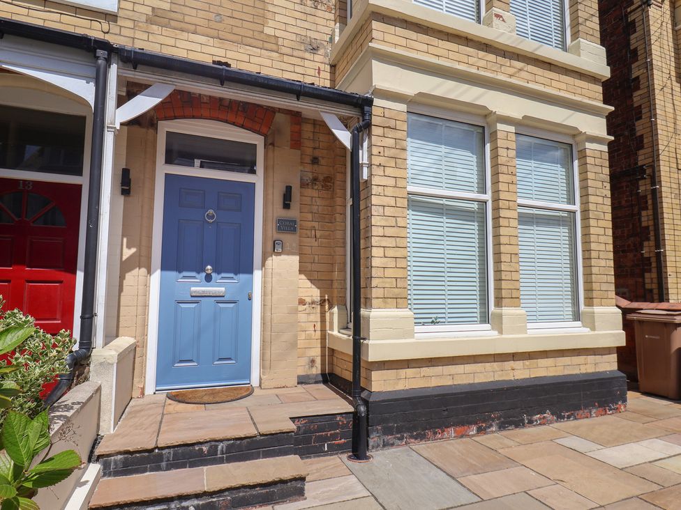 A front entrance with a blue door and brick wall at Coral Villa in Bridlington