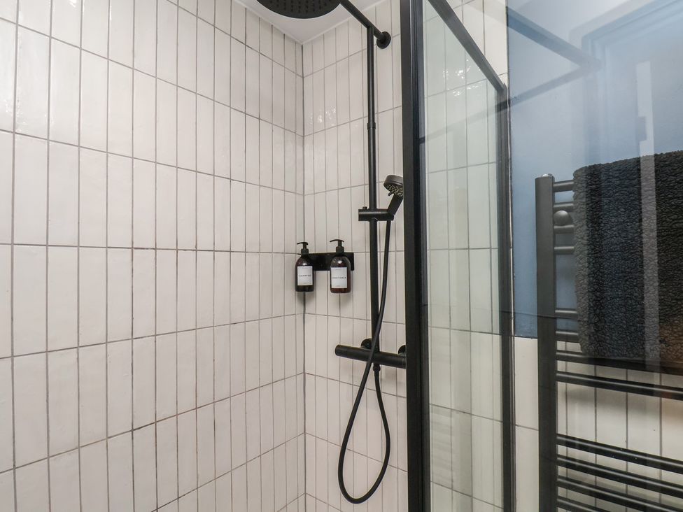 A shower with a black showerhead and soap dispenser at Coral Villa in Bridlington