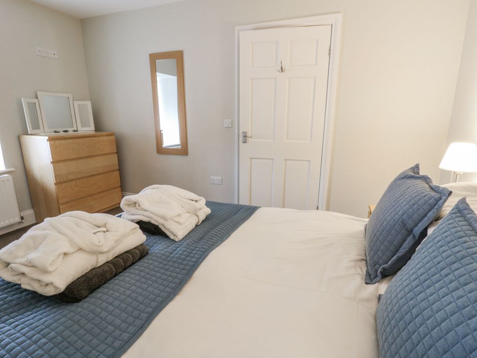 A bedroom with a bed, dresser, mirror and towels at Station Hall in Cilgerran