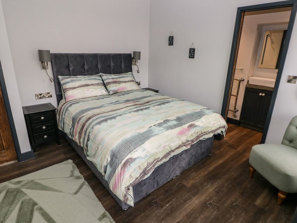 A bedroom with a bed and a bathroom door at 9 Brython Place Tenby