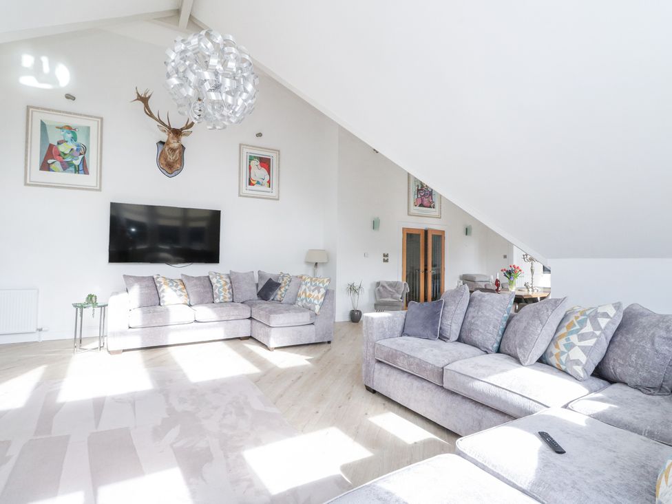 A living room with grey sofas a mounted deer head and a wall-mounted TV at Macgregor Ranch in Achnabobane near Spean Bridge