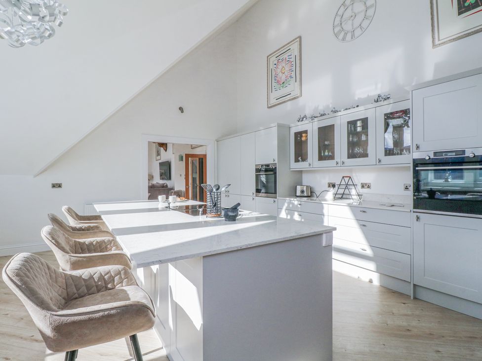 A kitchen with bar stools at a countertop and white cabinets at Macgregor Ranch in Achnabobane near Spean Bridge