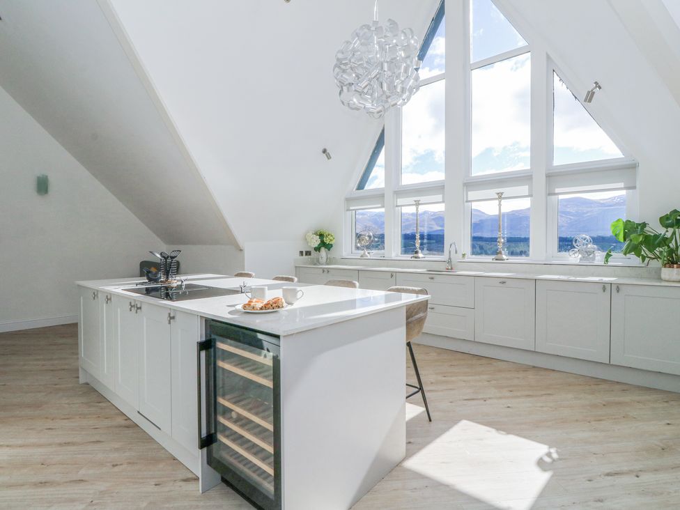 A kitchen with an island counter and large windows overlooking mountains at Macgregor Ranch in Achnabobane near Spean Bridge