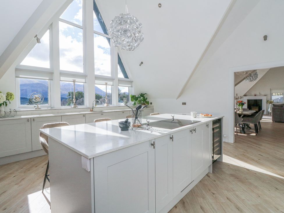 A kitchen with an island counter and large windows showing mountains at Macgregor Ranch Achnabobane near Spean Bridge