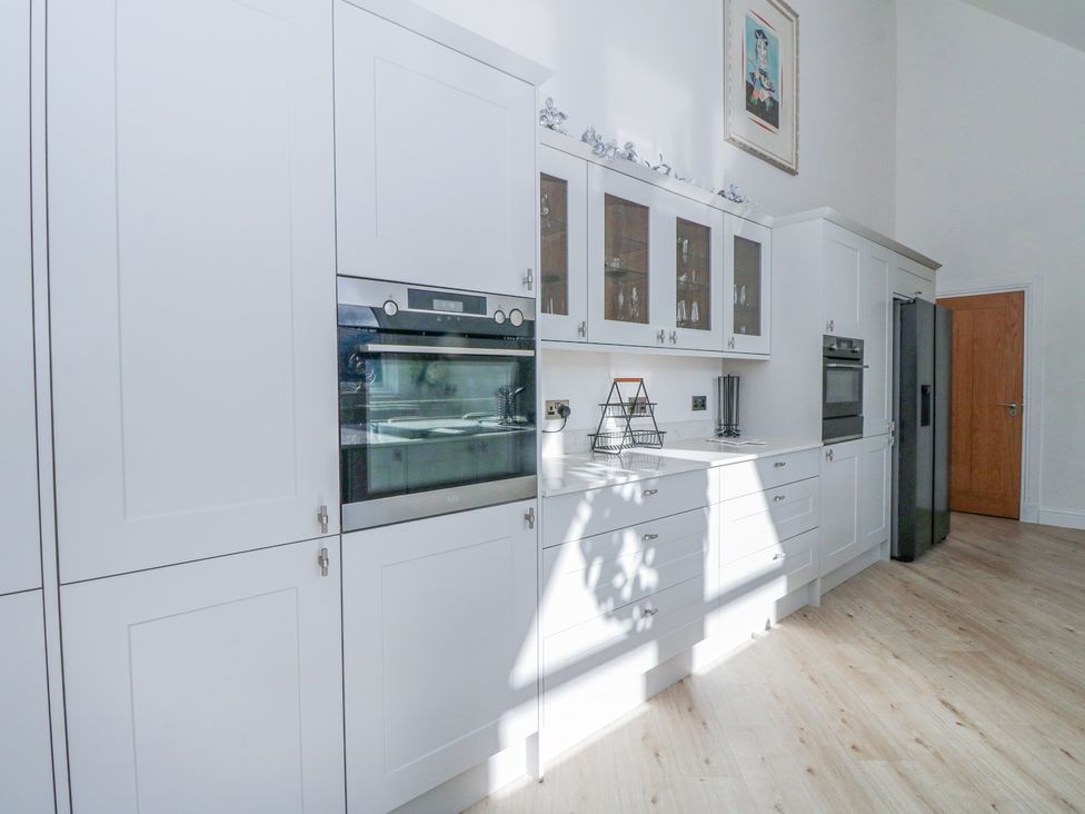 A kitchen with white cabinets built in ovens glass door upper cabinets and a refrigerator at Macgregor Ranch in Achnabobane near Spean Bridge
