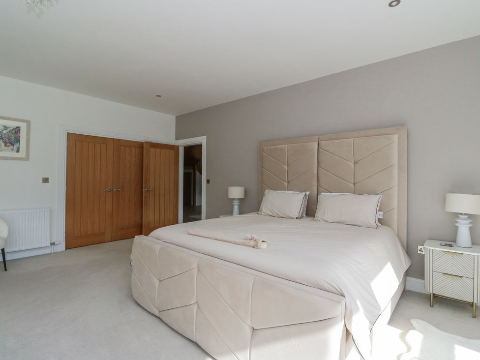 A bedroom with a bed a nightstand a lamp wooden doors and a framed picture at Macgregor Ranch in Achnabobane near Spean Bridge