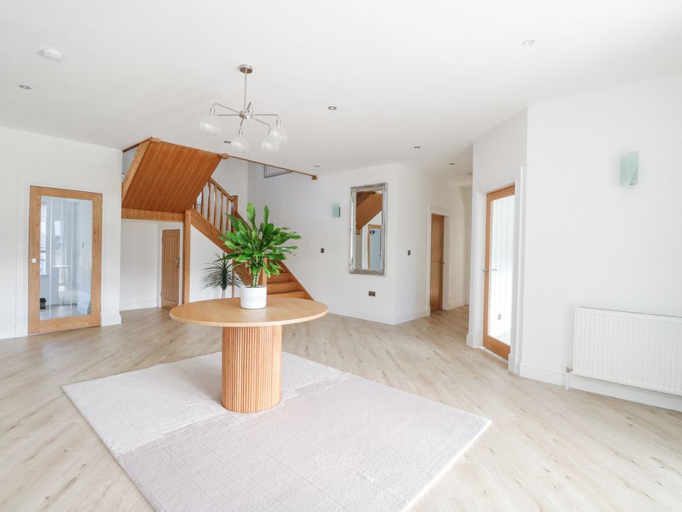 An empty room with a round wooden table and plant in the center a staircase wooden doors and a large mirror on the wall at Macgregor Ranch in Achnabobane near Spean Bridge