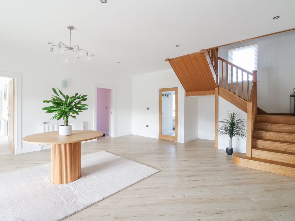 A staircase with wooden steps and railing next to a round wooden table with a plant on top on a rug in a room at Macgregor Ranch in Achnabobane near Spean Bridge