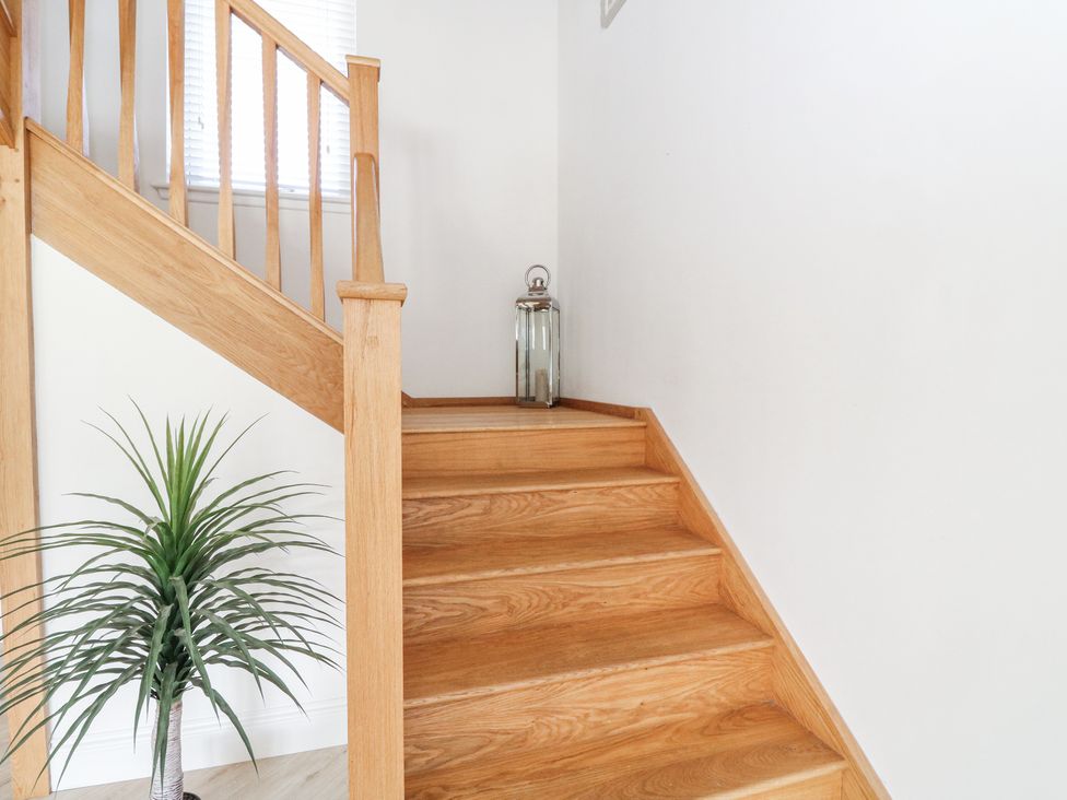 A wooden staircase with a metal lantern on the landing and a potted plant beside it at Macgregor Ranch in Achnabobane near Spean Bridge