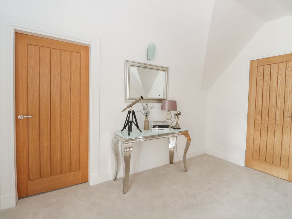 A hallway with two wooden doors and a mirrored console table with a lamp a telescope and books at Macgregor Ranch in Achnabobane near Spean Bridge