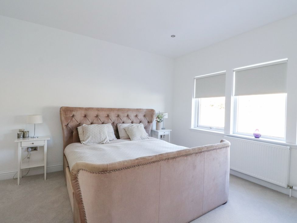 A bedroom with a bed and bedside tables with lamps and windows with blinds at Macgregor Ranch in Achnabobane near Spean Bridge