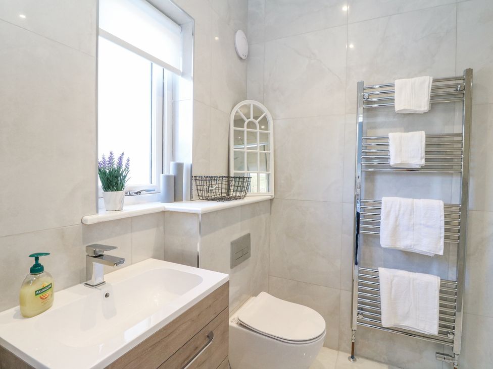 A bathroom with a sink and faucet a window with a plant and towels a mirror and a towel rack with towels Macgregor Ranch Achnabobane near Spean Bridge