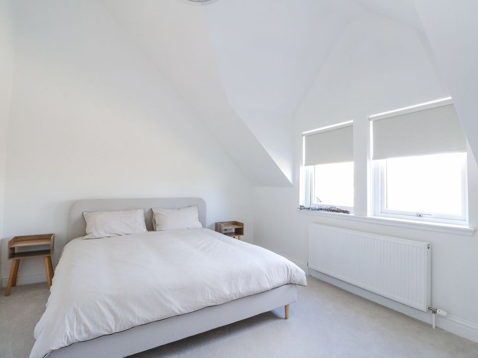 A bedroom with a double bed and two wooden bedside tables under slanted ceilings at Macgregor Ranch in Achnabobane near Spean Bridge
