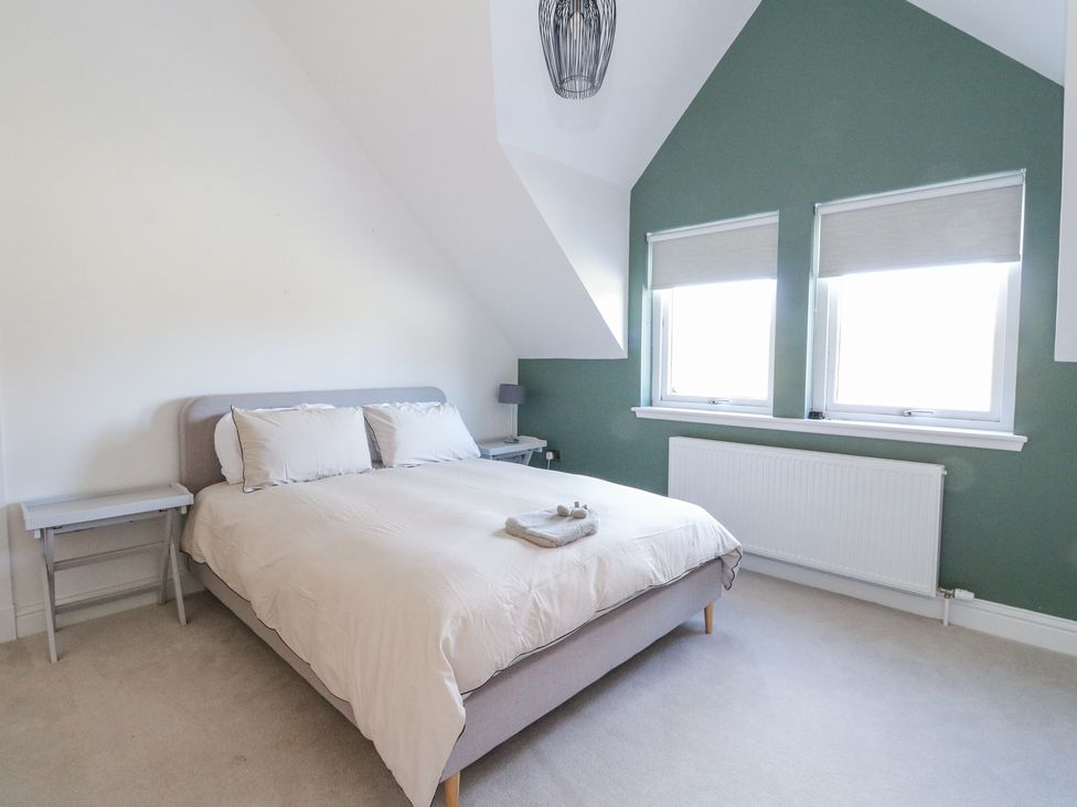 A bedroom with a double bed two windows and two bedside tables at Macgregor Ranch in Achnabobane near Spean Bridge
