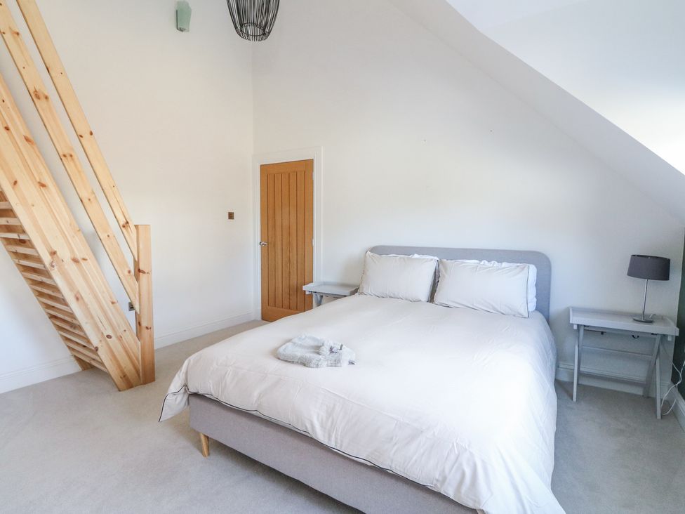 A bedroom with a double bed two side tables a wooden door and wooden stairs at Macgregor Ranch in Achnabobane near Spean Bridge