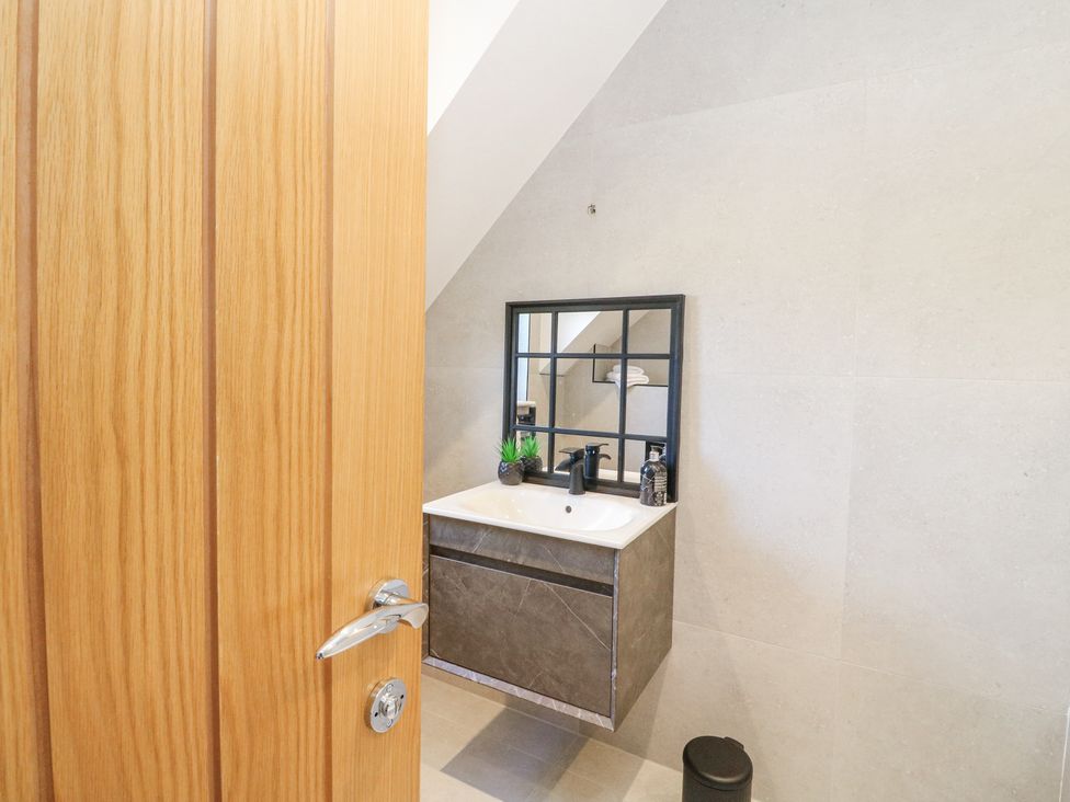 A bathroom sink with a mirror above it and a small trash can on the floor at Macgregor Ranch in Achnabobane near Spean Bridge