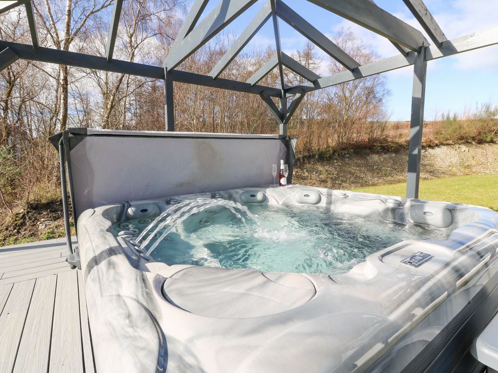 An outdoor hot tub with water jets under a metal frame shelter at Macgregor Ranch in Achnabobane near Spean Bridge