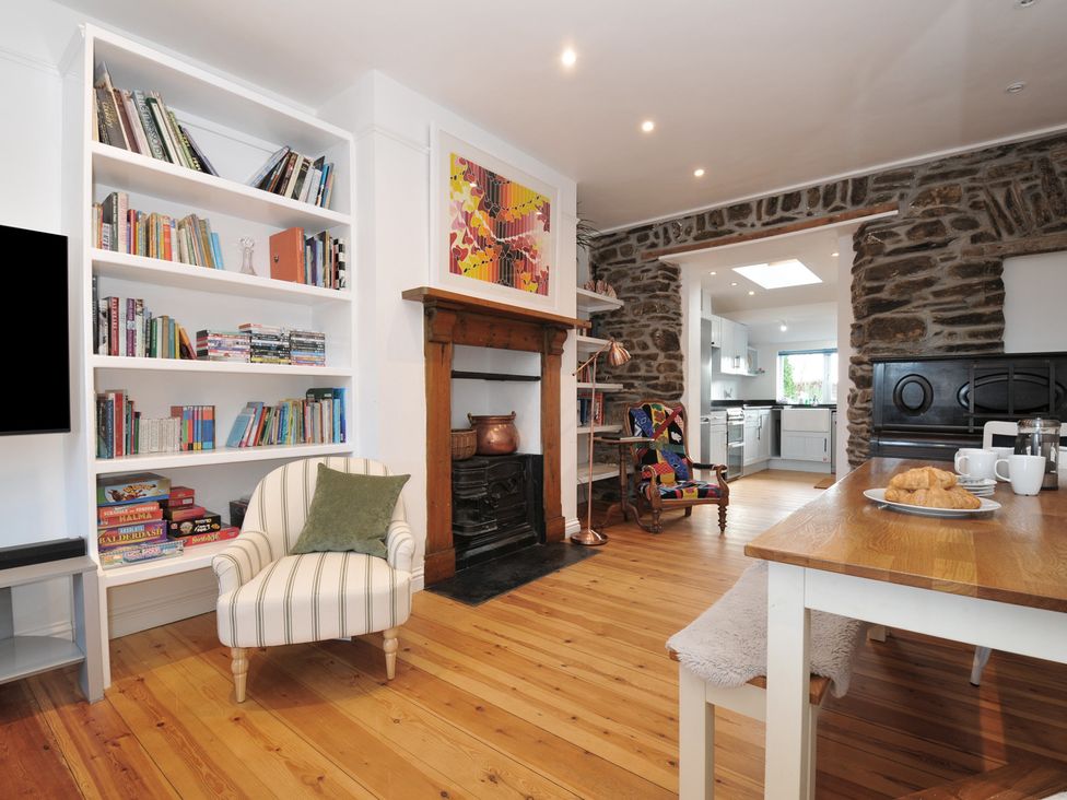 A living room with a bookshelf and a dining area at 2 Glyddins 1910 in Rock