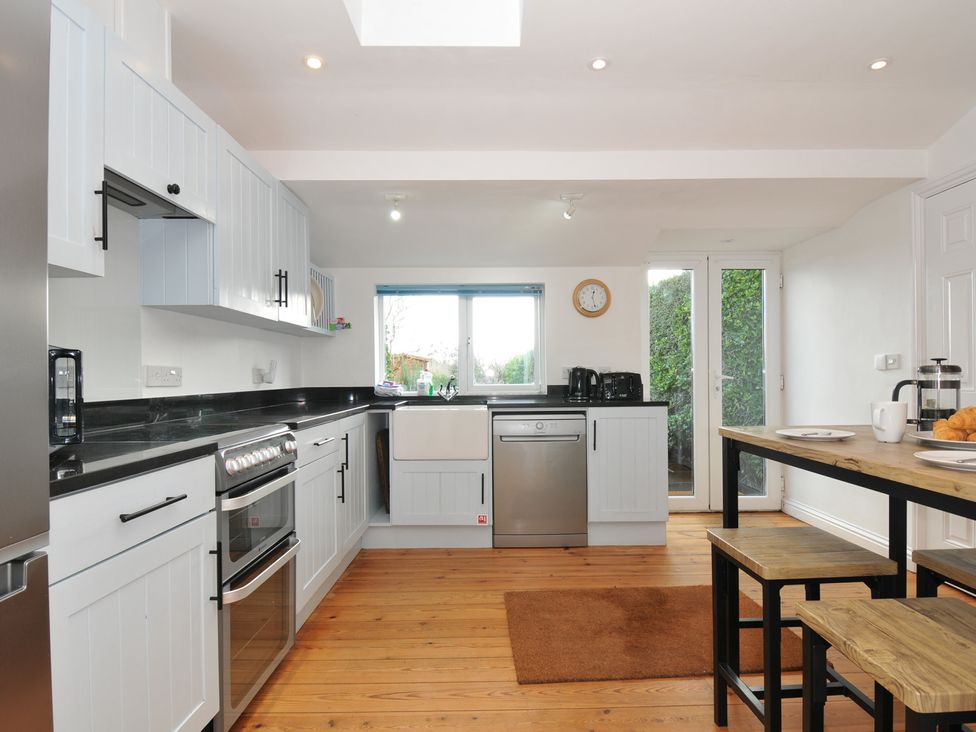 A kitchen with cabinets, stove, and wooden table at 2 Glyddins 1910 in Rock