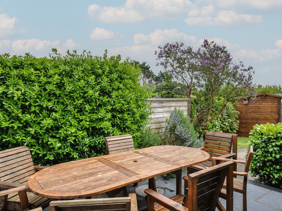 A garden with a wooden table and chairs at 2 Glyddins 1910 Rock