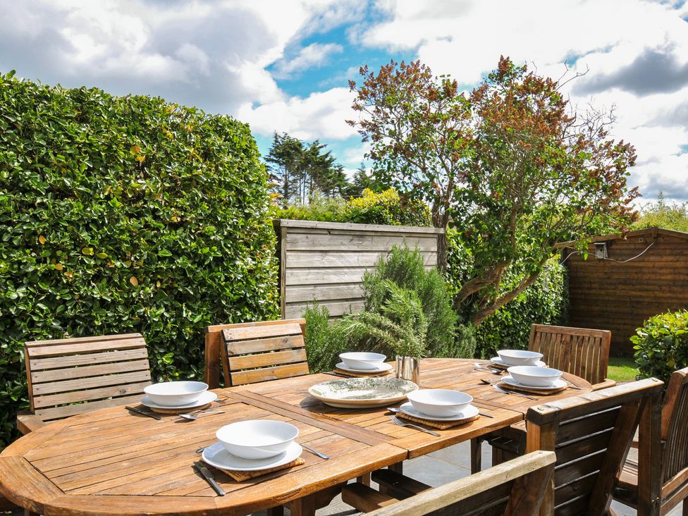 An outdoor dining area with a wooden table set for meals at 2 Glyddins 1910 in Rock