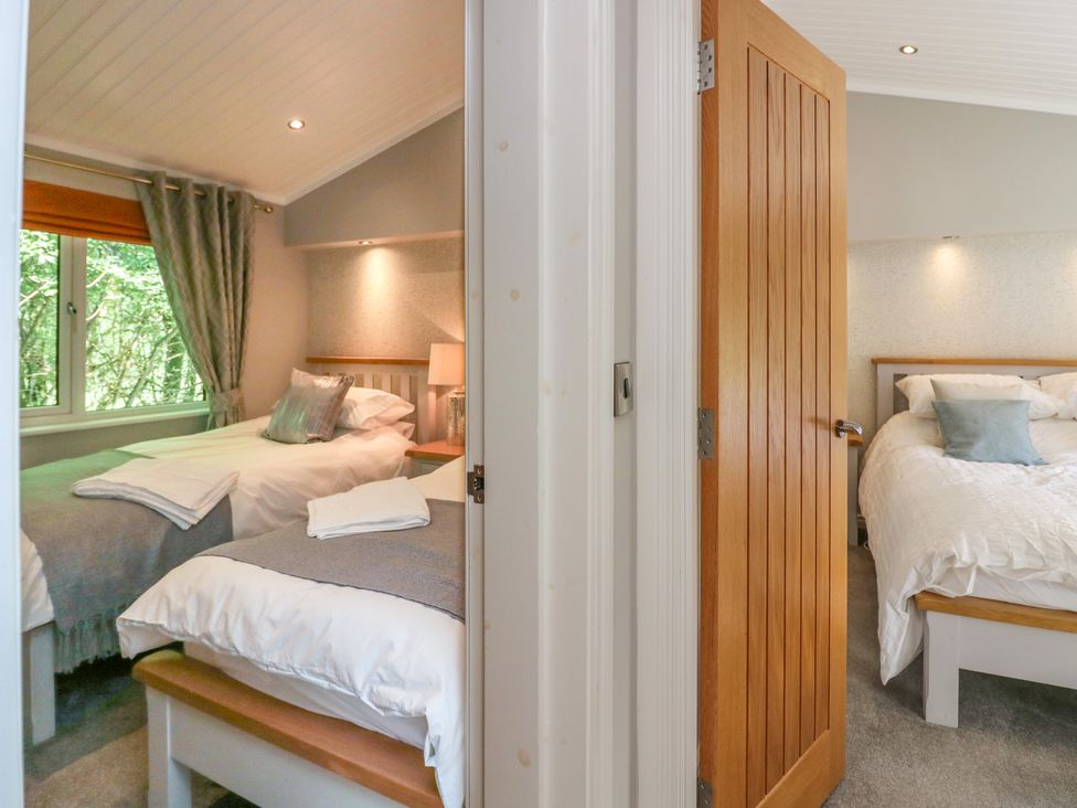 Two bedrooms with beds pillows bedside lamps and a window with curtains at Waterside Lodge 55A Bowness White Cross Bay near Windermere
