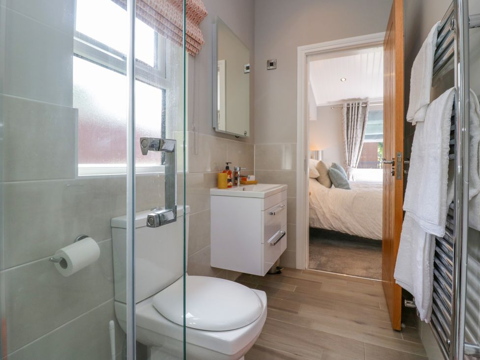 A bathroom with a toilet sink and towel rack leading into a bedroom at Waterside Lodge 55A Bowness White Cross Bay near Windermere