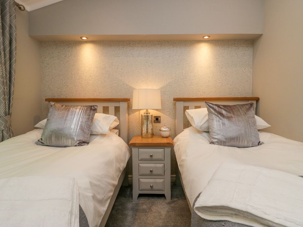 A bedroom with two single beds a nightstand with a lamp and a decorative item at Waterside Lodge 55A Bowness White Cross Bay near Windermere