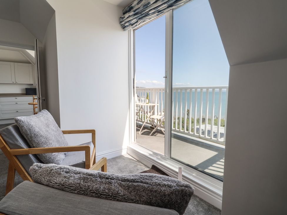 A living room with a chair and sliding door leading to a balcony at 3 Harbour Heights in Lyme Regis