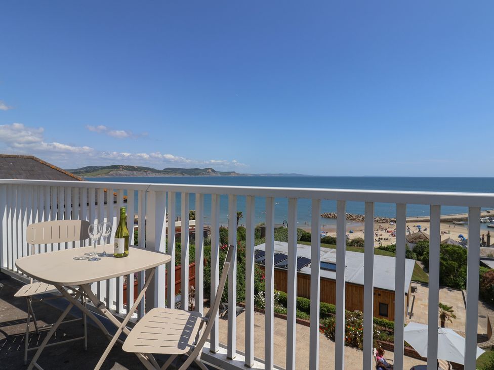 A balcony with a table and chairs overlooking the beach at 3 Harbour Heights Lyme Regis