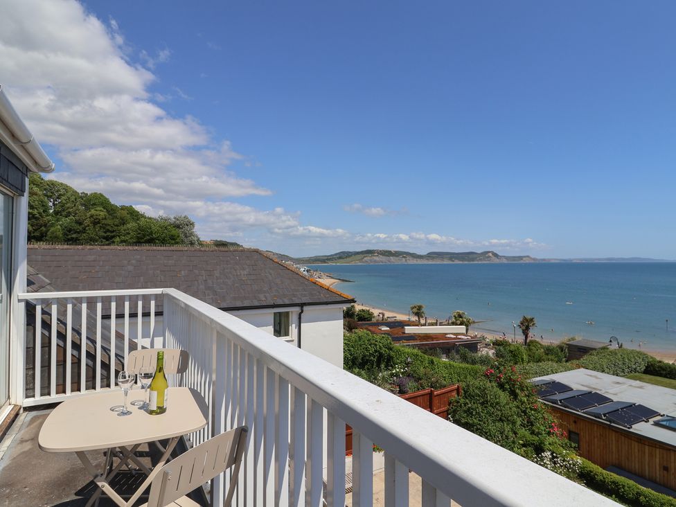 A balcony with a table and chairs overlooking the sea at 3 Harbour Heights Lyme Regis