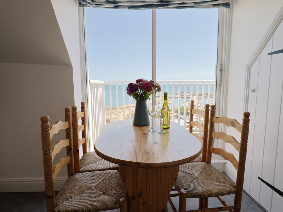 A dining area with a table and chairs overlooking the ocean at 3 Harbour Heights in Lyme Regis