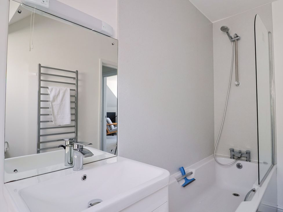 A bathroom with a sink, bathtub, and towel rack at 3 Harbour Heights in Lyme Regis