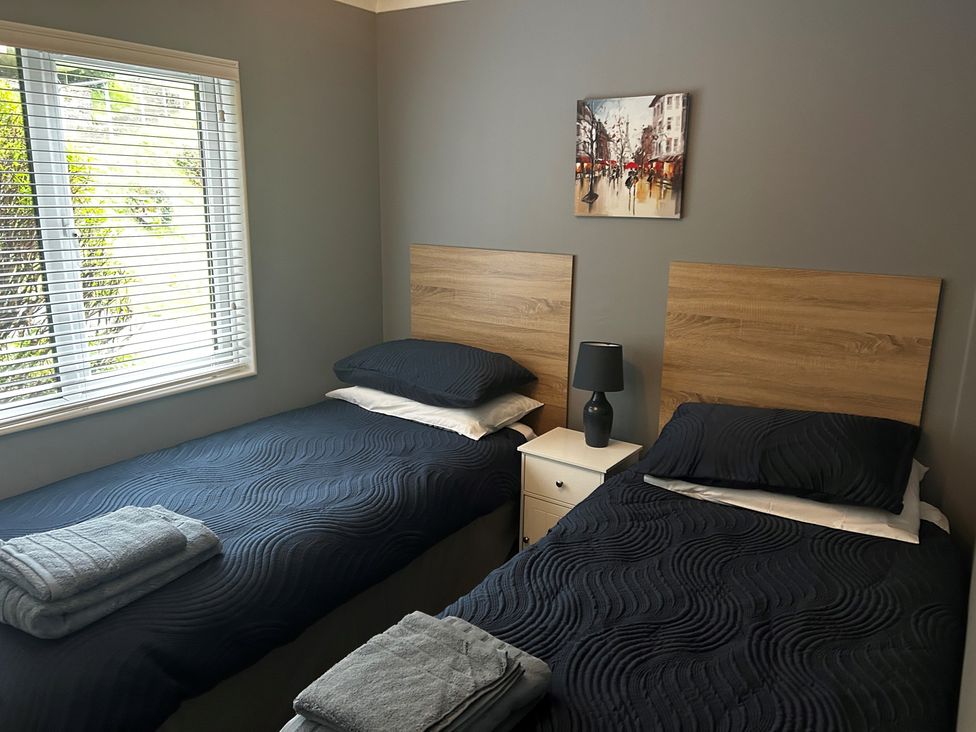 A bedroom with two beds and a painting at 22 Two Little Ducks in Lynton