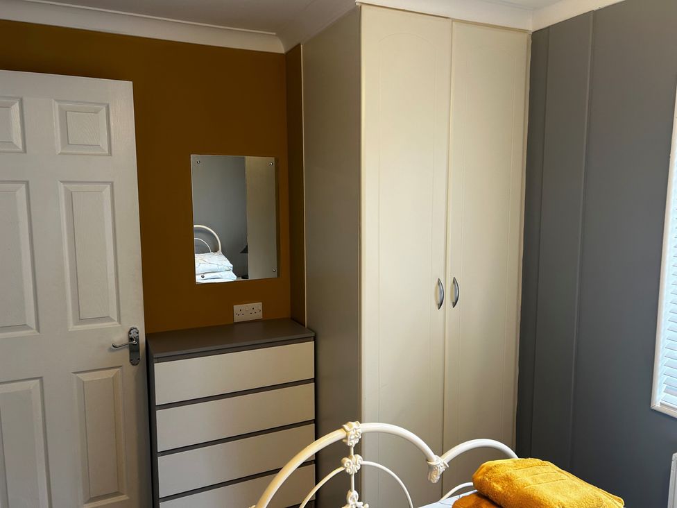 A bedroom with a wardrobe and mirror at 22 Two Little Ducks in Lynton