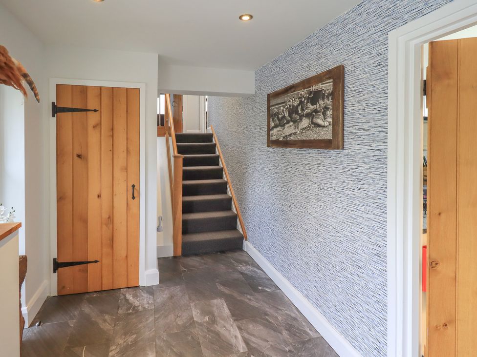 A hallway with staircase and wooden door at Haystacks in Troutbeck