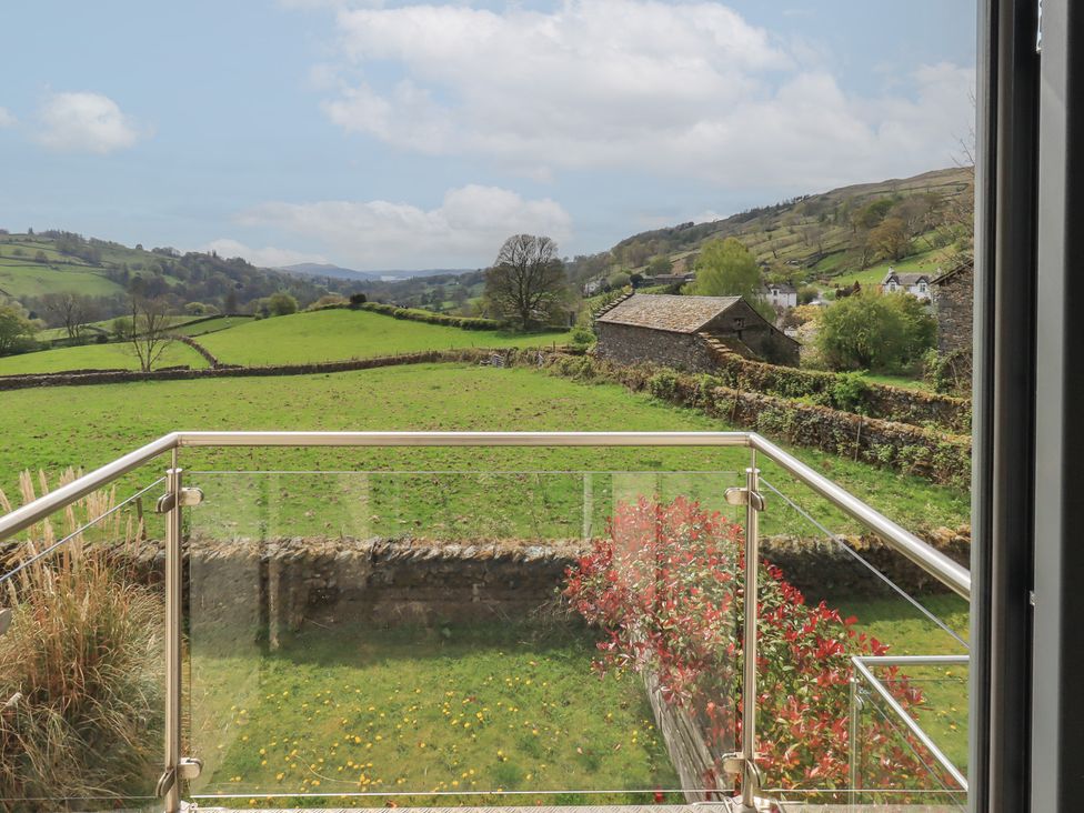 A balcony with a view of a green field and trees at Haystacks in Troutbeck
