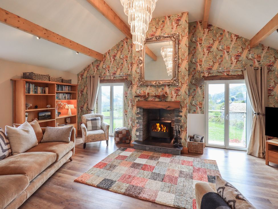 A living room with a sofa, bookshelf, and fireplace at Haystacks in Troutbeck