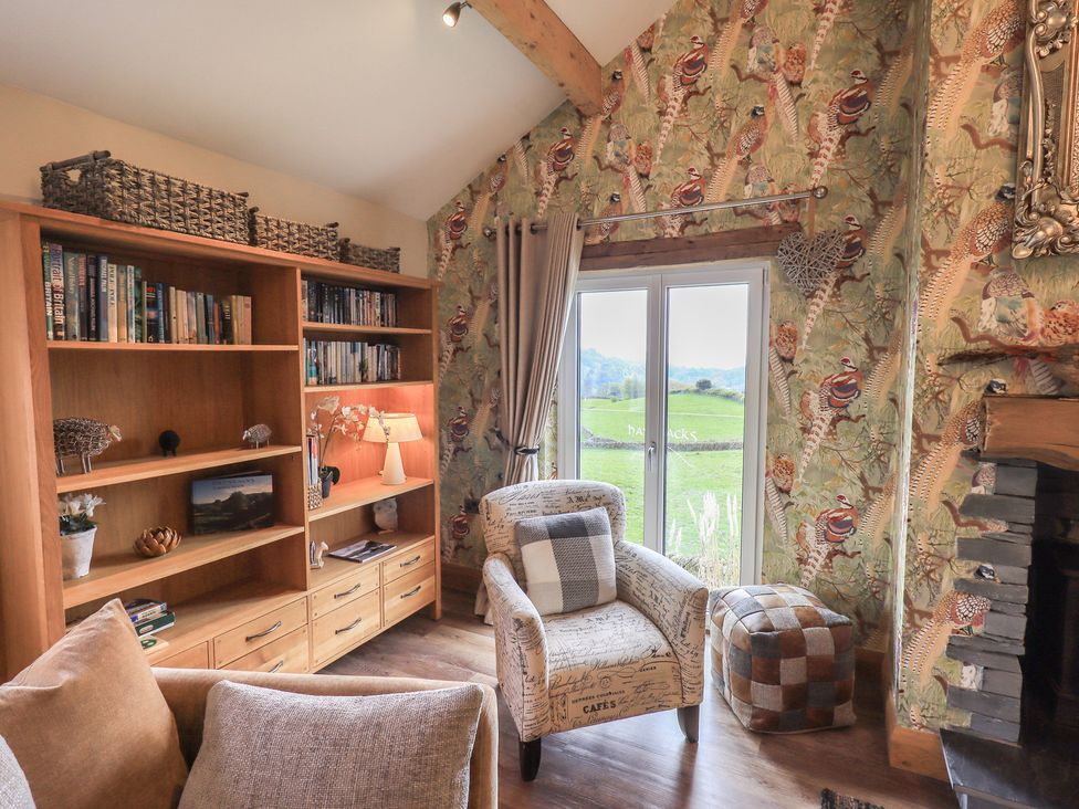 A living room with a bookshelf and armchair at Haystacks in Troutbeck