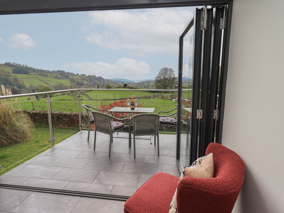 A balcony with a table and chairs overlooking the landscape at Haystacks in Troutbeck