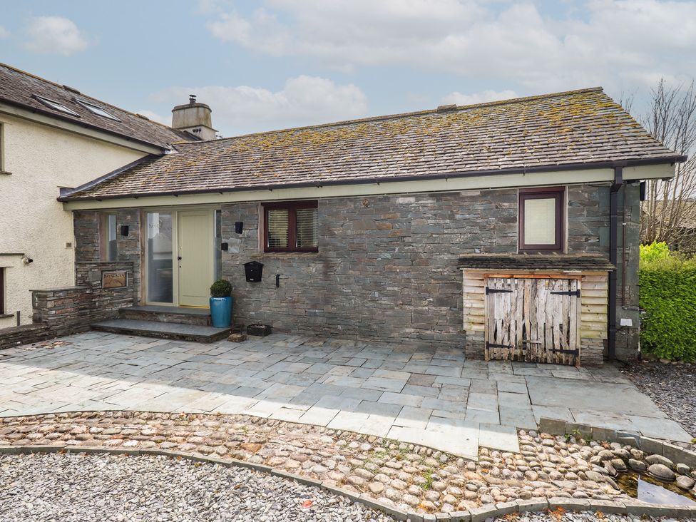 An outdoor view of a house with stone wall and patio at Haystacks in Troutbeck