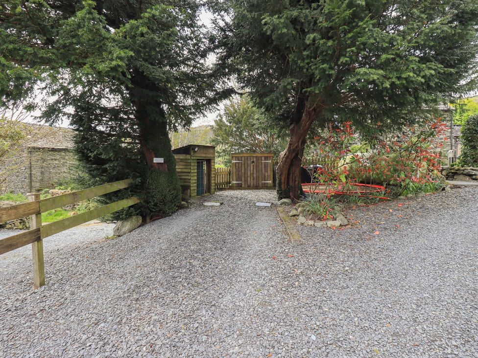 A gravel driveway with a wooden gate and trees at Haystacks in Troutbeck