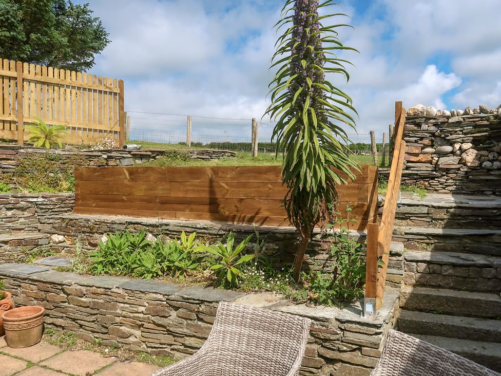 A garden with stone stairs and a wooden fence at Hilldene Treknow